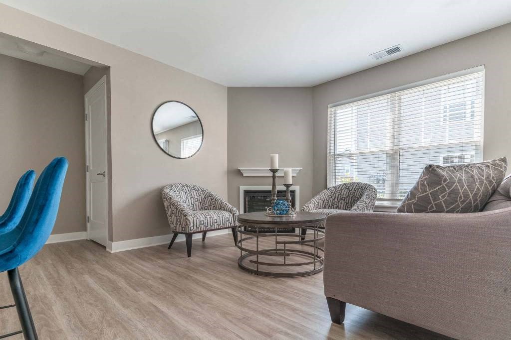 View of living area of great room showing fireplace, large windows, plank flooring, and foyer