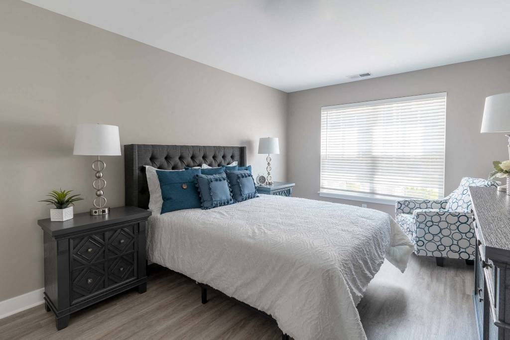 View of spacious bedroom with plank flooring, large windows