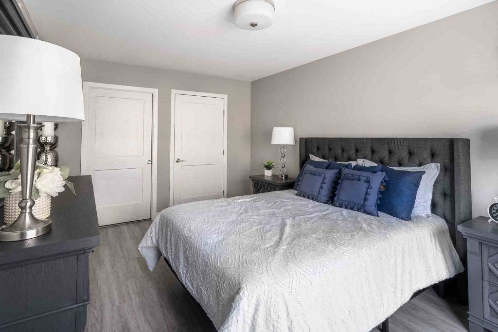 View of spacious bedroom with plank flooring, and doors to ensuite bathroom and walk-in closet