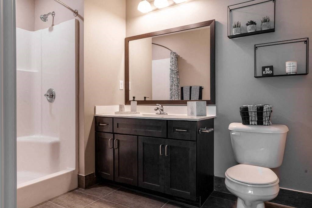 Primry bedroom's bathroom with large step-in shower, vanity, and tile flooring.