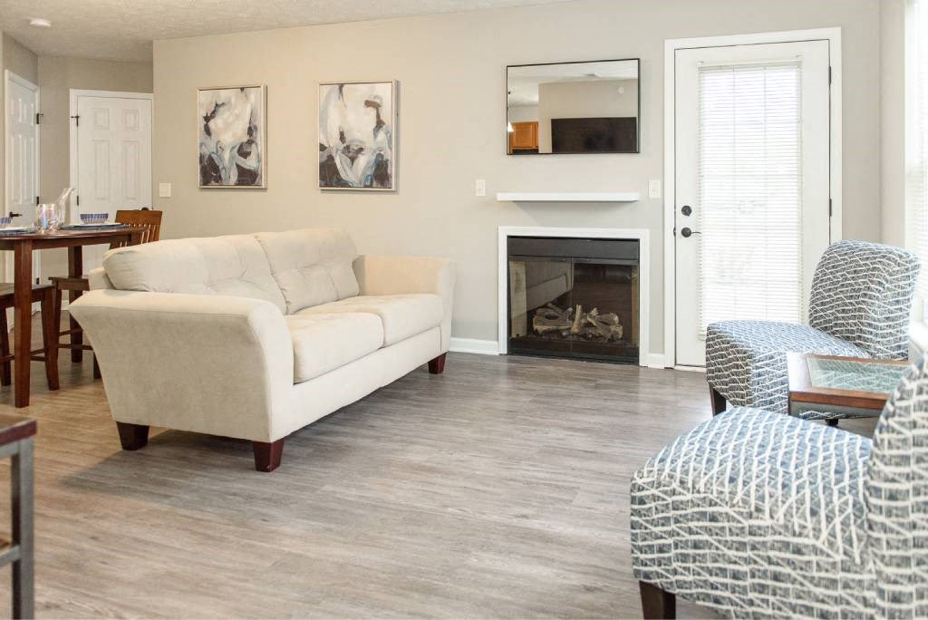View of great room from foyer showing living area with fireplace and door to private patio and dining area