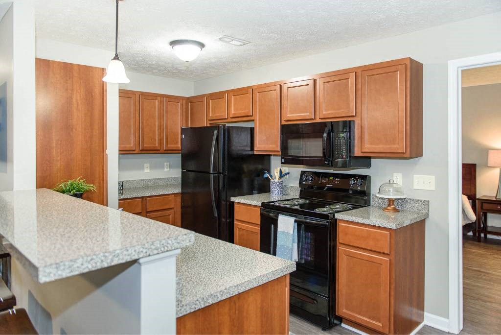 Well-equipped kitchen with black appliances, plenty of cupboard space, and brown cabinetry