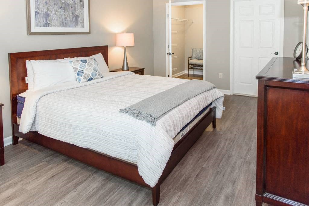 Spacious bedroom with plank flooring and view into walk-in closet (and door to ensuite bathroom)