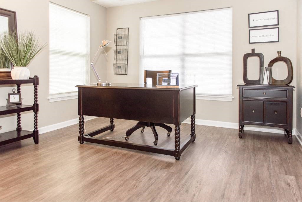 Second bedroom with plank flooring  and large, bright windows being used as an office