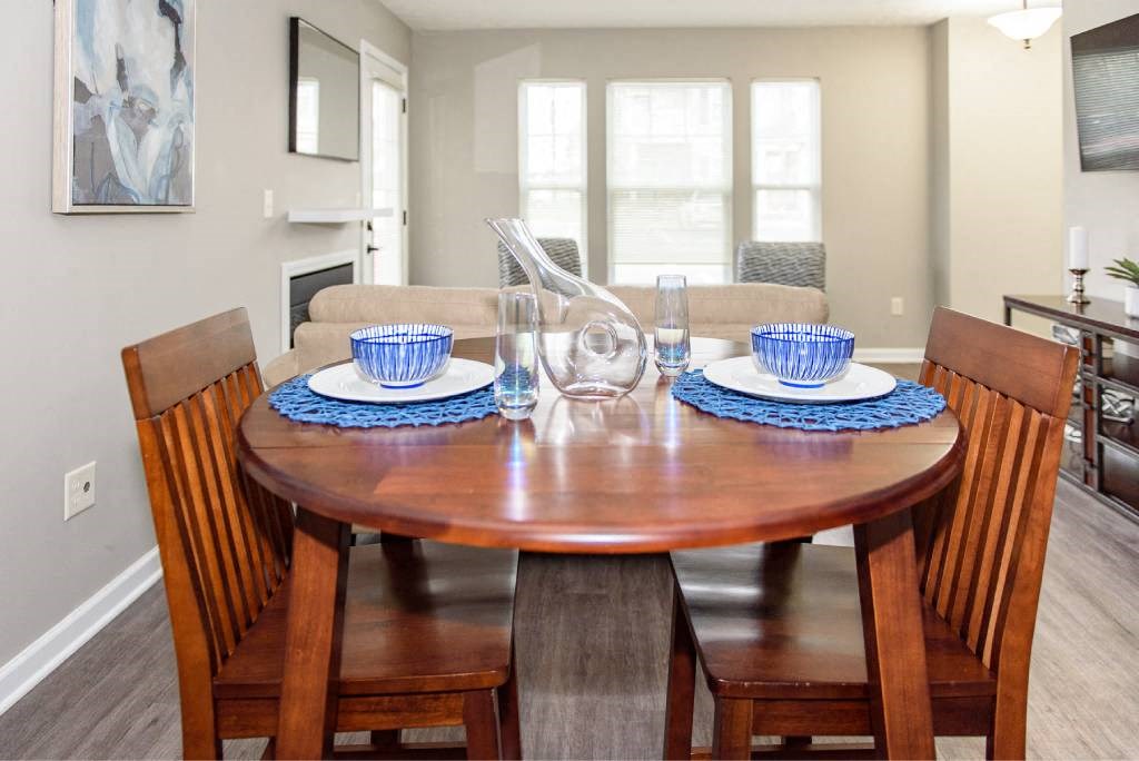 View of dining area of great room with large, bright window in the background and plank flooring