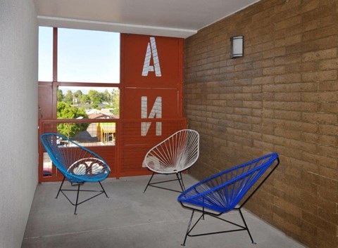 two blue chairs on a porch next to a brick wall