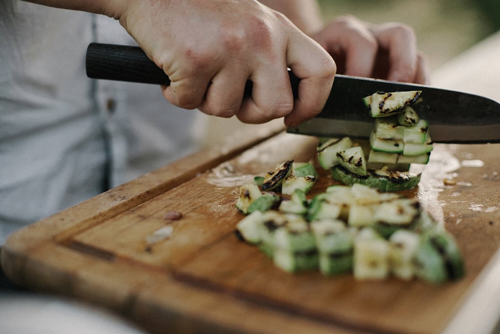 a person cutting up cucumbers on a cutting board with a knife