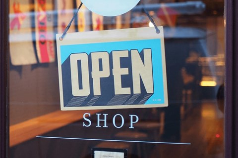 a blue open shop sign in the window of a store