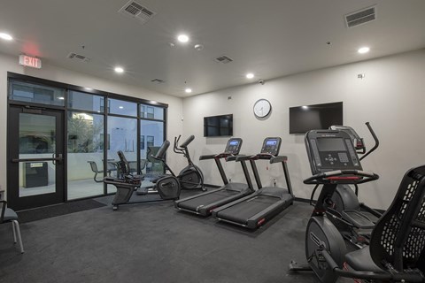 a gym with cardio machines and a tv