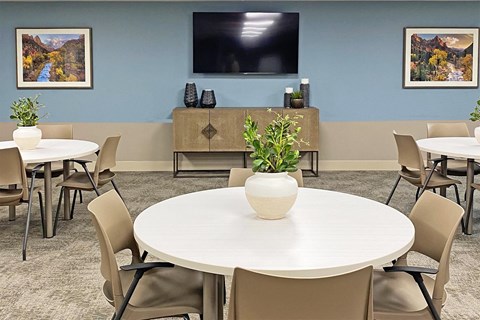 a conference room with tables and chairs and a television on the wall