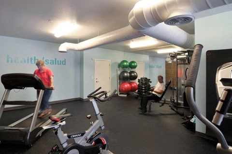 a gym with exercise equipment and people in it