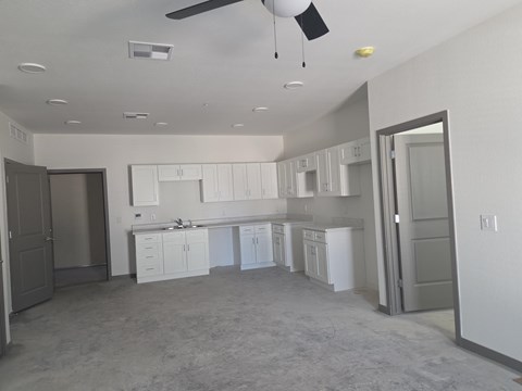 A spacious kitchen with white cabinets and a ceiling fan.
