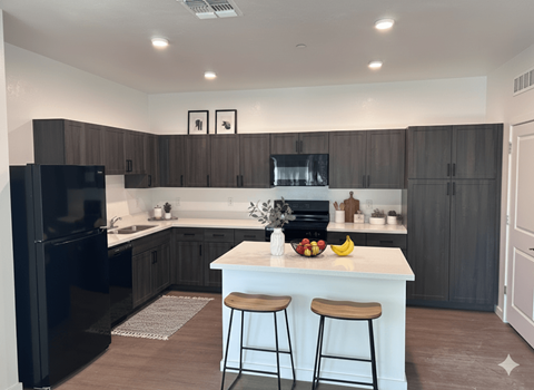 A kitchen with a black refrigerator and white countertops.