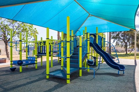 A playground with a blue slide and yellow poles.