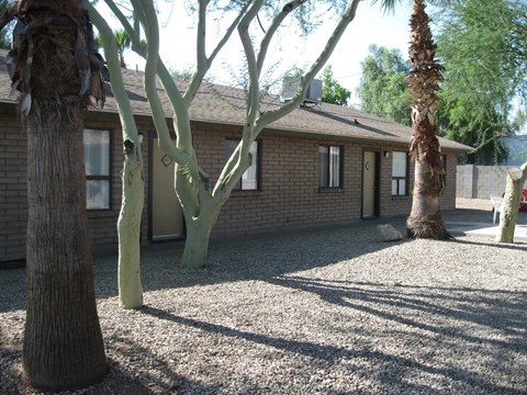 a house with trees and gravel in front of it