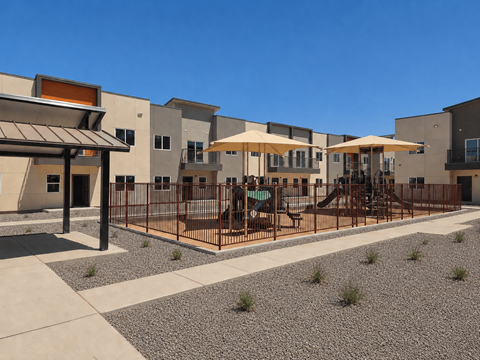 A playground area in front of a building with a brown fence.