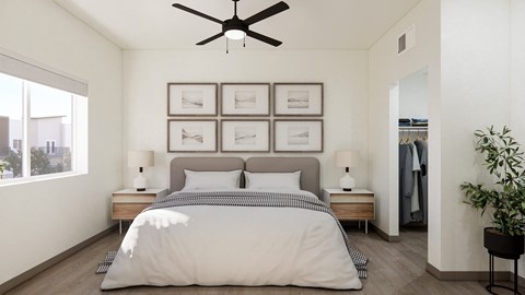 A bedroom with a bed, two lamps, a ceiling fan, and a wall with framed pictures.