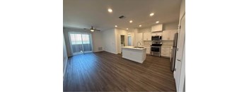 A spacious kitchen with white cabinets and a wooden floor.