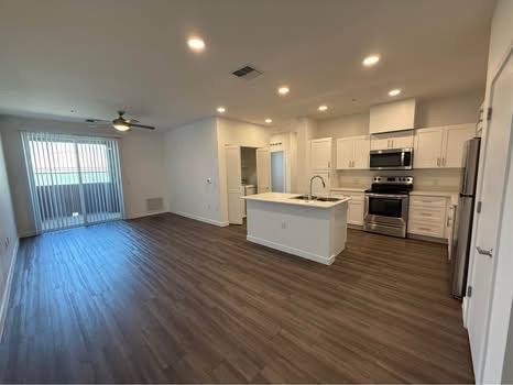 A spacious kitchen with white cabinets and a wooden floor.