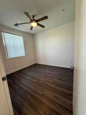 A room with a ceiling fan and wooden flooring.