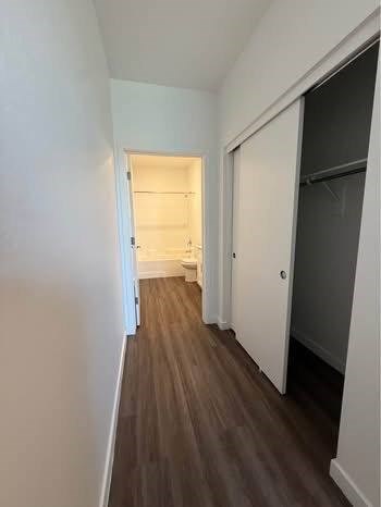 A long hallway with white walls and wood flooring.