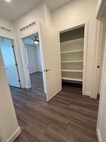 A room with a fan and shelves in it.