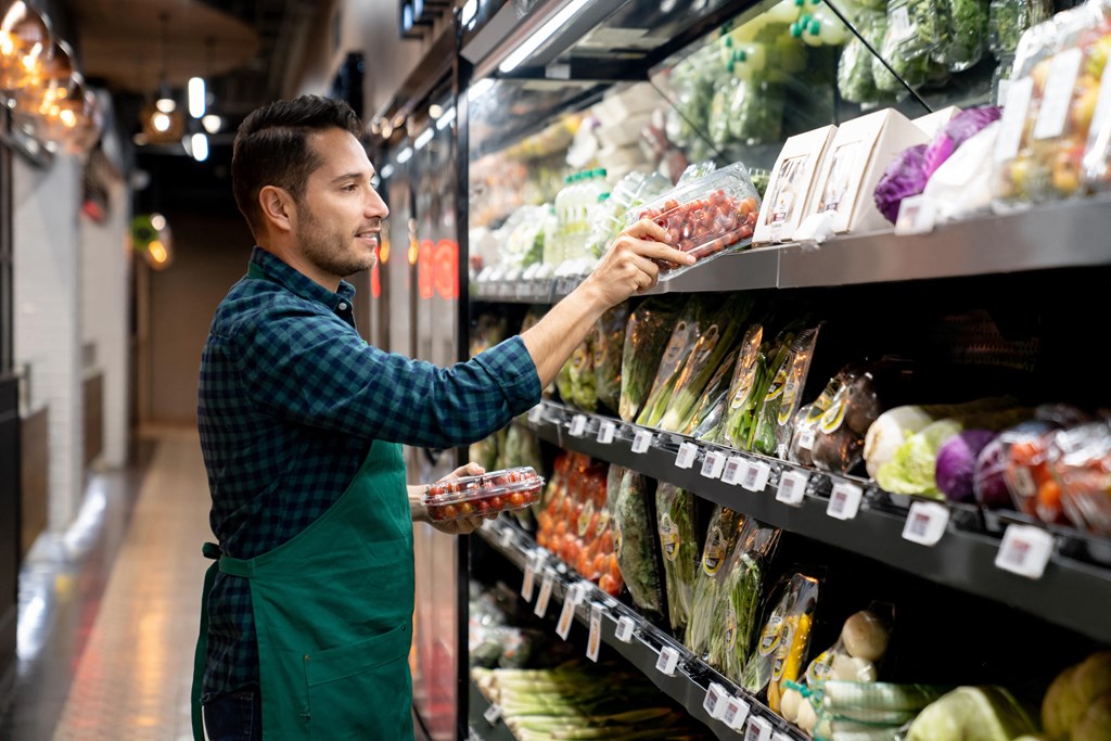 a man in a grocery store selecting food from a shelf