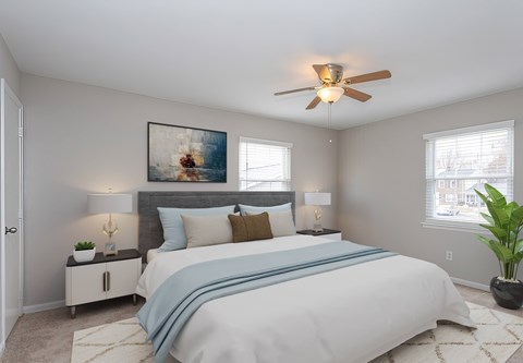 A bedroom with a large bed and a ceiling fan.