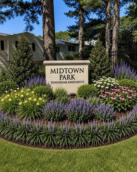 A sign that says Midtown Park in front of some flowers.