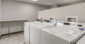 a row of white washing machines in a laundromat