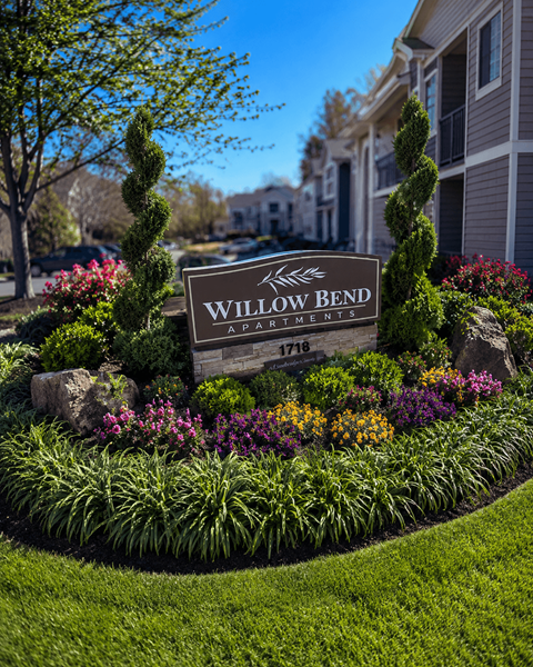 A sign that says Willow Bend in front of a flower bed.