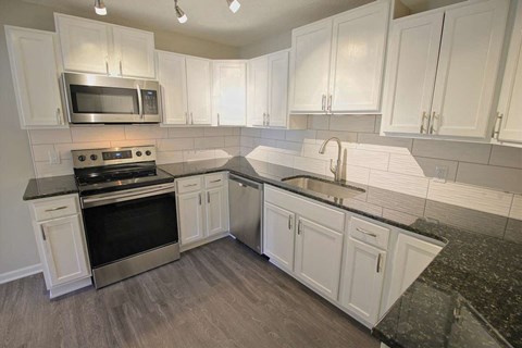 a kitchen with white cabinets and a sink and a stove