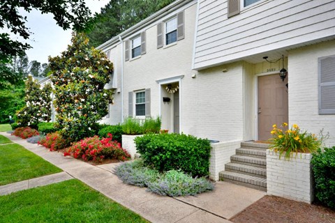 a white house with a sidewalk and landscaping in front of it