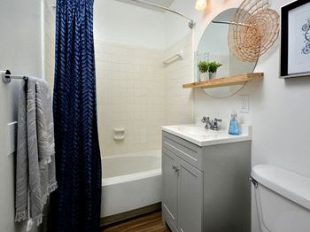 a small bathroom with a sink and a tub and a shower curtain at Capital Flats & Magnolia Square Apartments, Raleigh, NC, 27601