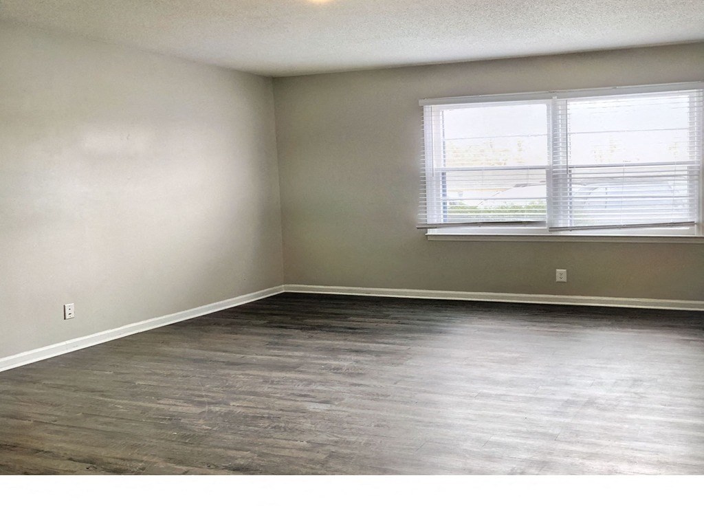 an empty living room with wood floors and two windows