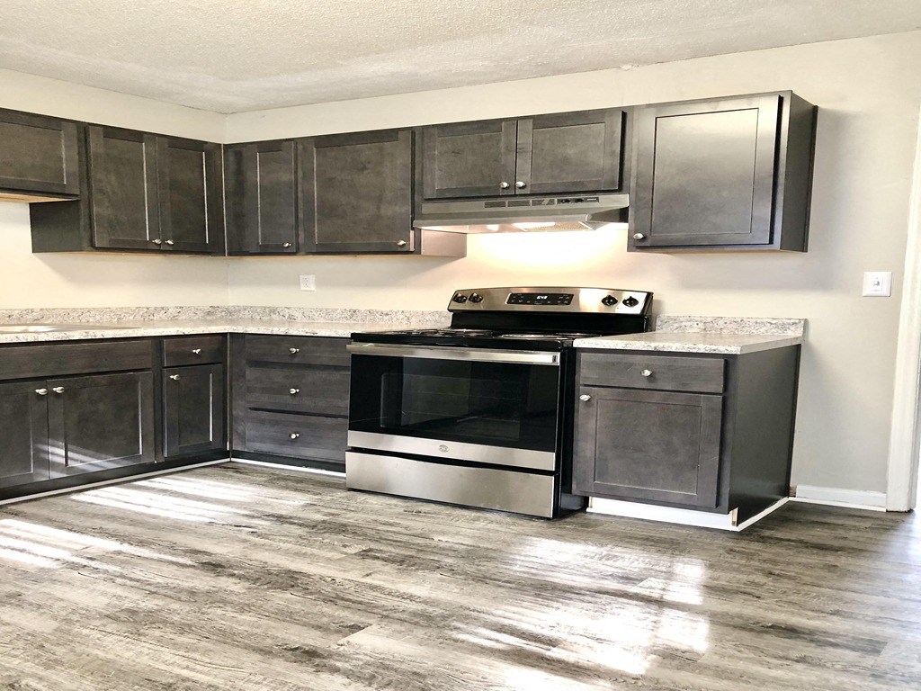 an empty kitchen with black cabinets and stainless steel appliances
