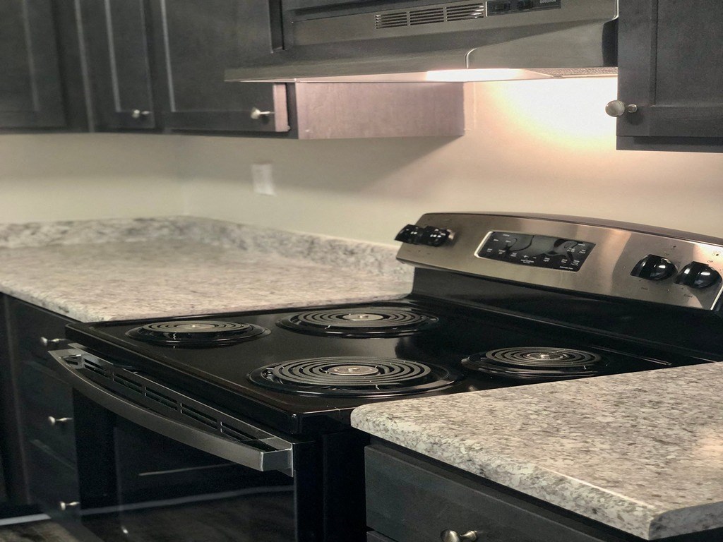 a kitchen with a stove and granite counter tops