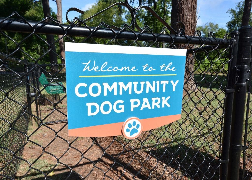 a welcome to the community dog park sign on a fence