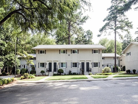 a white house with a street and trees in front of it