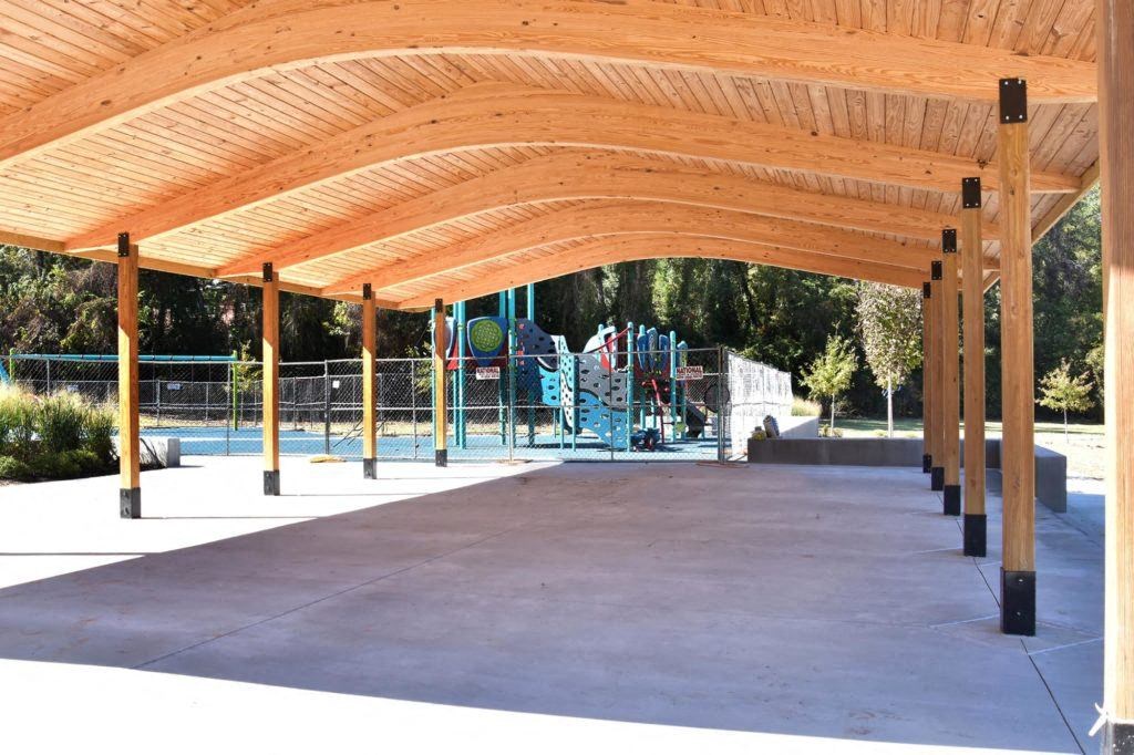 a covered pavilion with a playground in the background