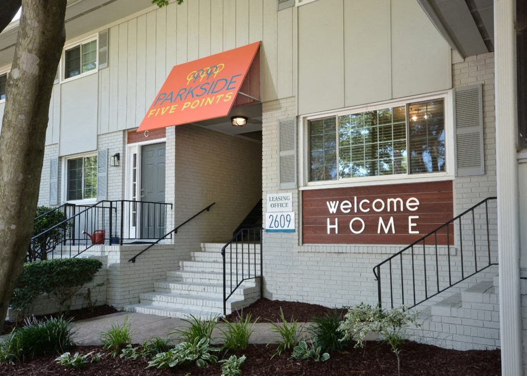 the front entrance of an apartment building with a welcome home sign