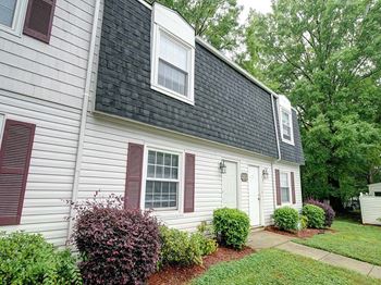 a white house with a black roof and a sidewalk