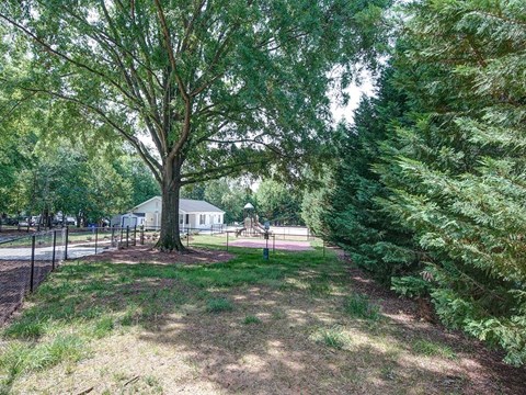 a park with a playground and trees in front of a house