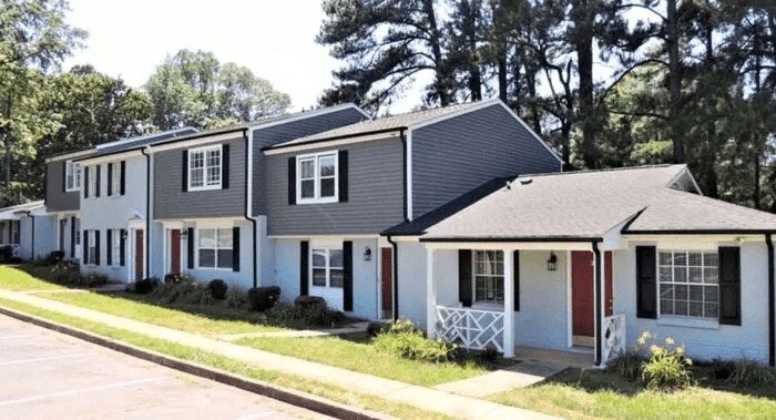a row of white houses with gray roofs and a sidewalk