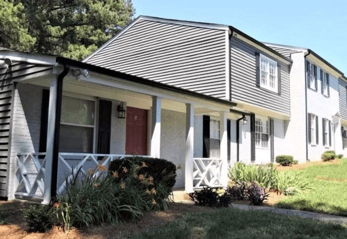 a white house with a porch and a red door