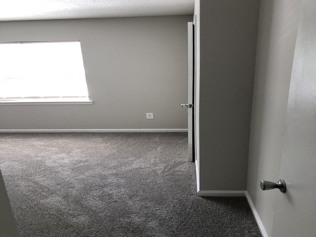 an empty room with a door open and a window