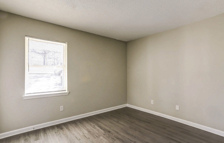 an empty bedroom with wood floors and a window