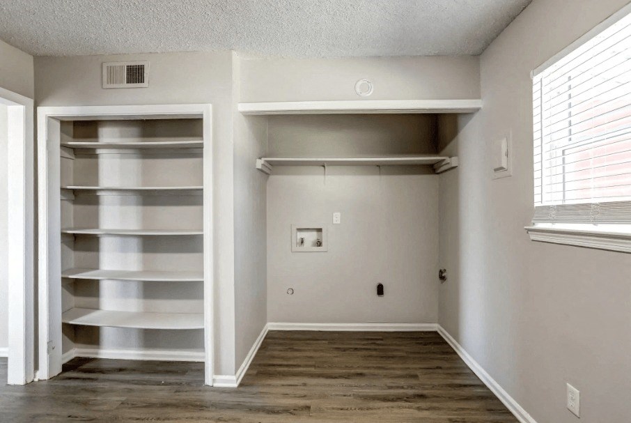 an empty room with white shelves and a window