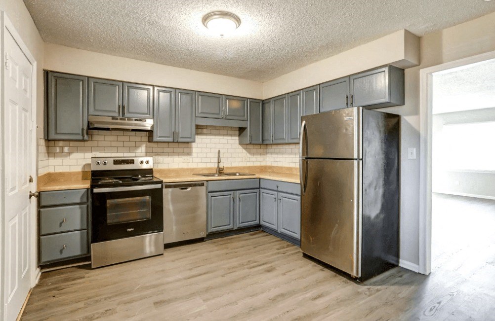 an empty kitchen with stainless steel appliances and blue cabinets