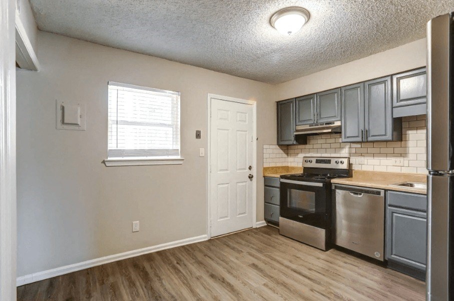 an empty kitchen with stainless steel appliances and gray cabinets